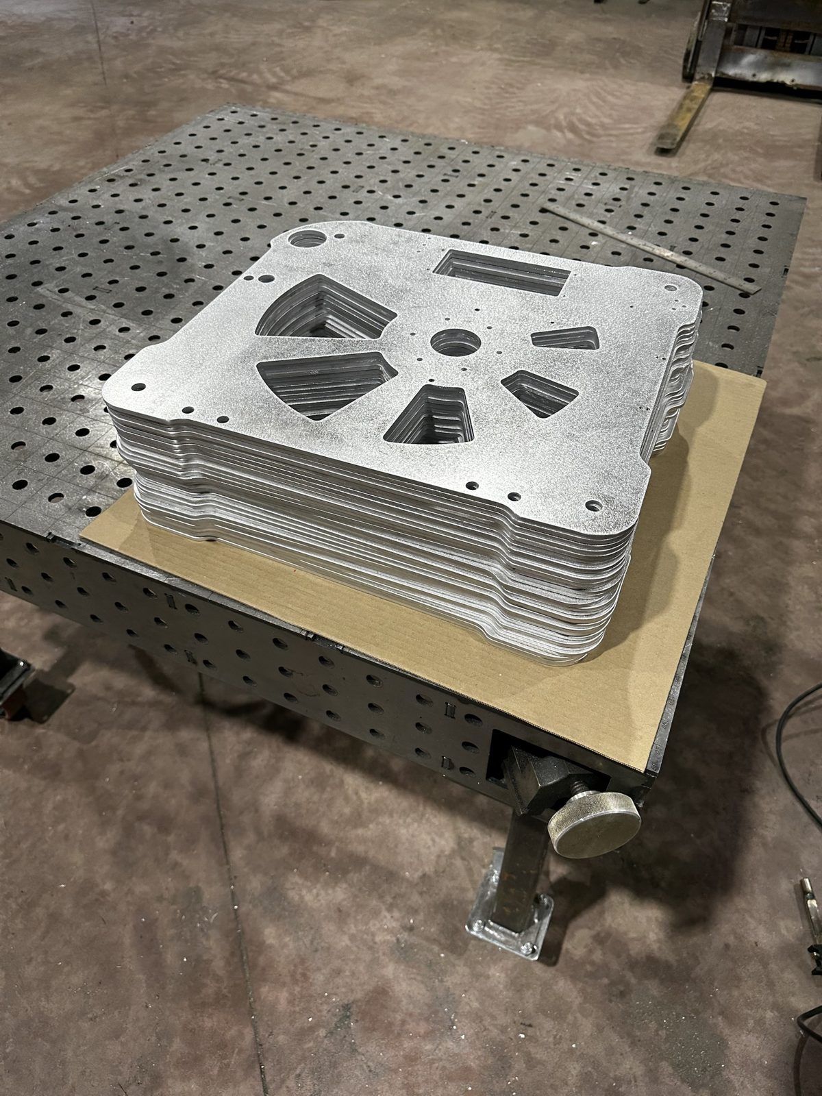 A stack of laser-cut aluminum production parts